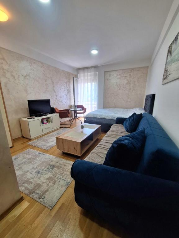 a living room with a blue couch and a bed at Apartman Selma - Bijelo Polje in Bijelo Polje