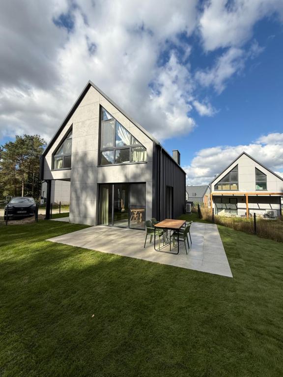 a house with a table and chairs in a yard at Aura Kaszub Lake&Forest in Łączyno