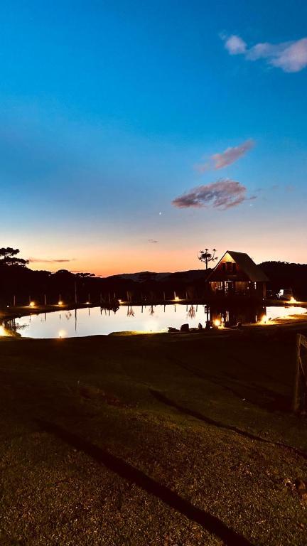 a view of a pond at night with the sun setting at Chalé do Lago - Refúgio Arara Azul in Urubici