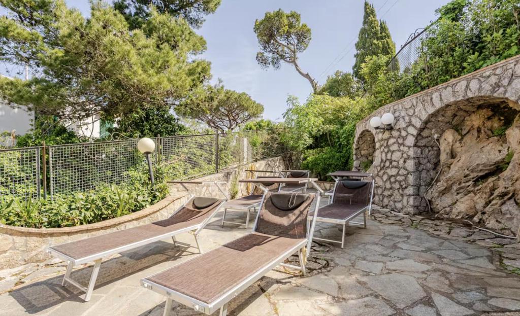 an outdoor patio with benches and a stone wall at Authentic Oasis - Villa La Solara in Anacapri