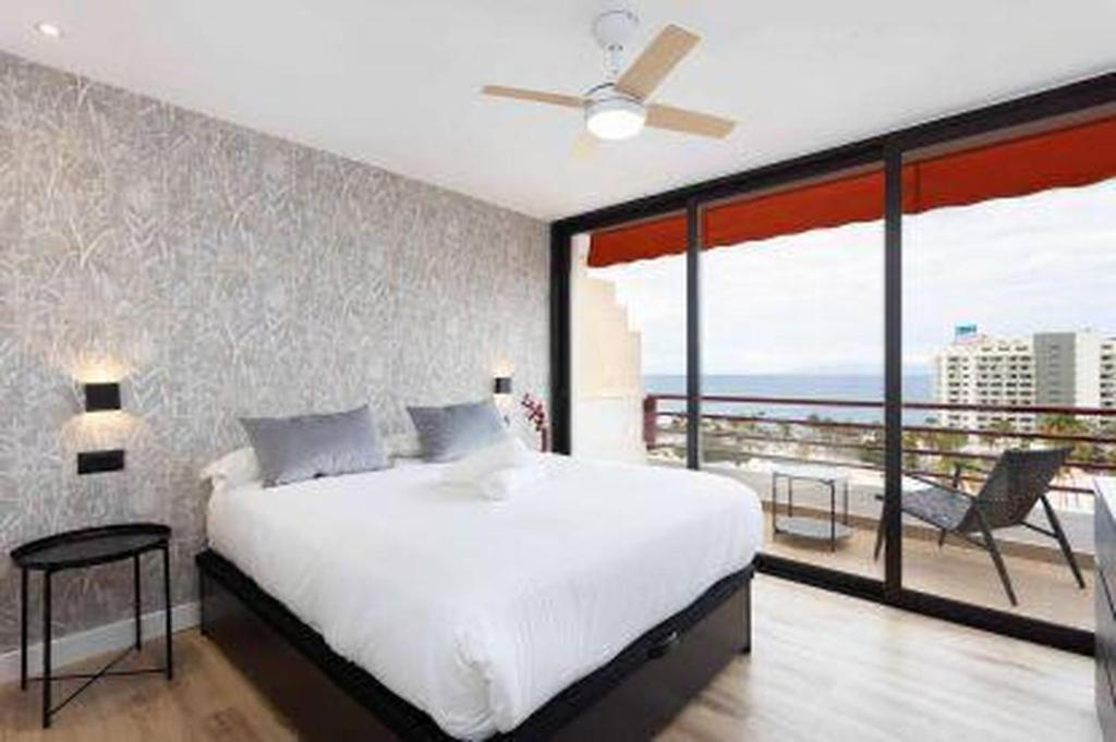 a bedroom with a large white bed and a balcony at Eden Rentals Olympia Sunny Seaviews in Playa de las Americas