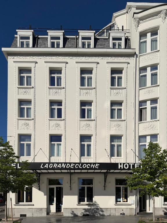 a large white building with a sign on it at Hotel La Grande Cloche in Brussels