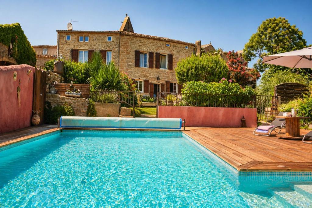 a swimming pool in front of a house at Domaine du Prieuré avec Piscine Ancien Couvent & Presbytère in Carcassonne