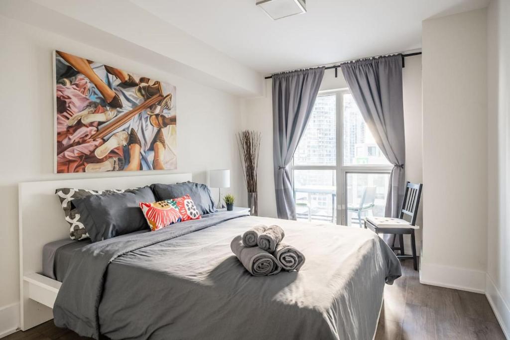 a bedroom with a large bed with a painting on the wall at Stylish 1BR plus Den Suite with Parking, Sleeps 4) in Toronto