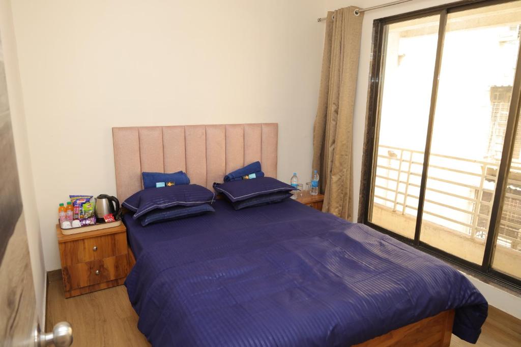 a bedroom with a bed with blue sheets and a window at FabHotel Aqua Pearl Inn in Navi Mumbai