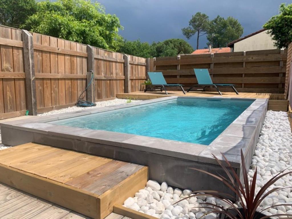 a swimming pool in a backyard with a wooden fence at Villa des Ponteils in Moliets-et-Maa