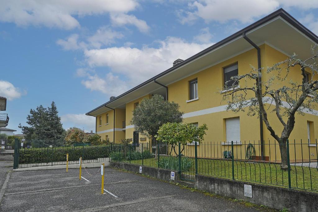 a yellow building with a fence in front of it at Casa vacanza Iris in Toscolano Maderno
