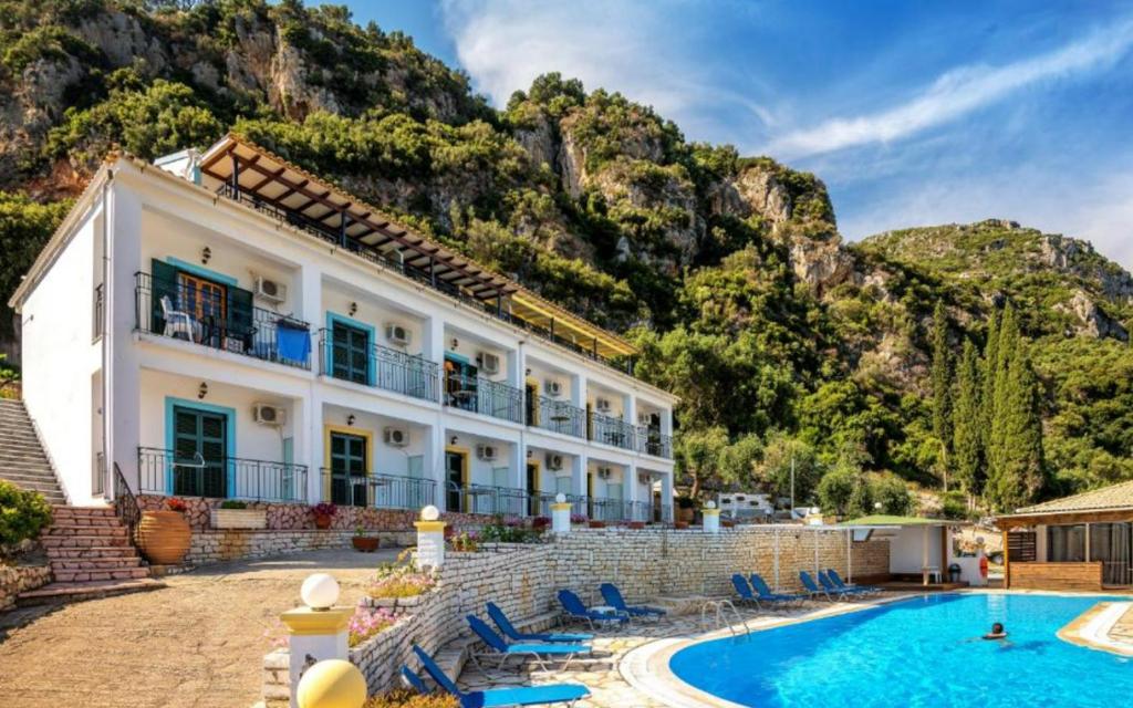 a villa with a swimming pool in front of a mountain at Fotini Studios in Paleokastritsa