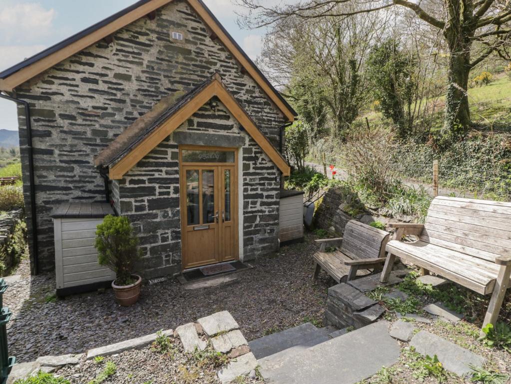 a small brick building with a wooden door and a bench at Ysgoldy in Dolwyddelan