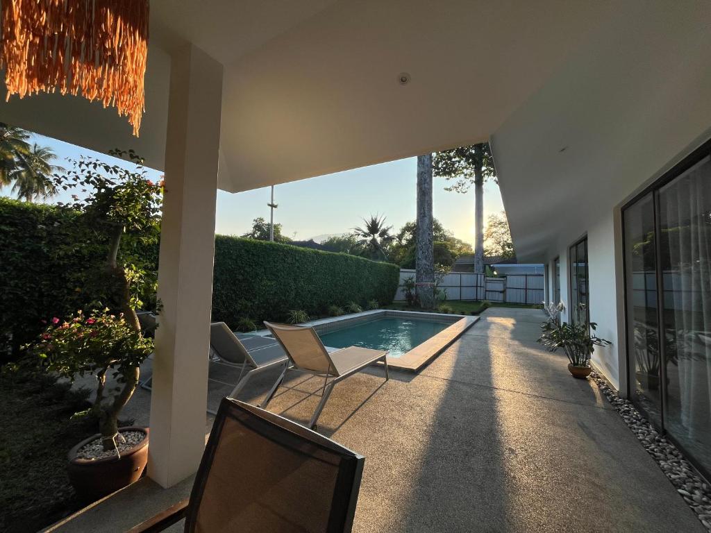 a patio with two chairs and a swimming pool at Maprao Villa in Mae Nam