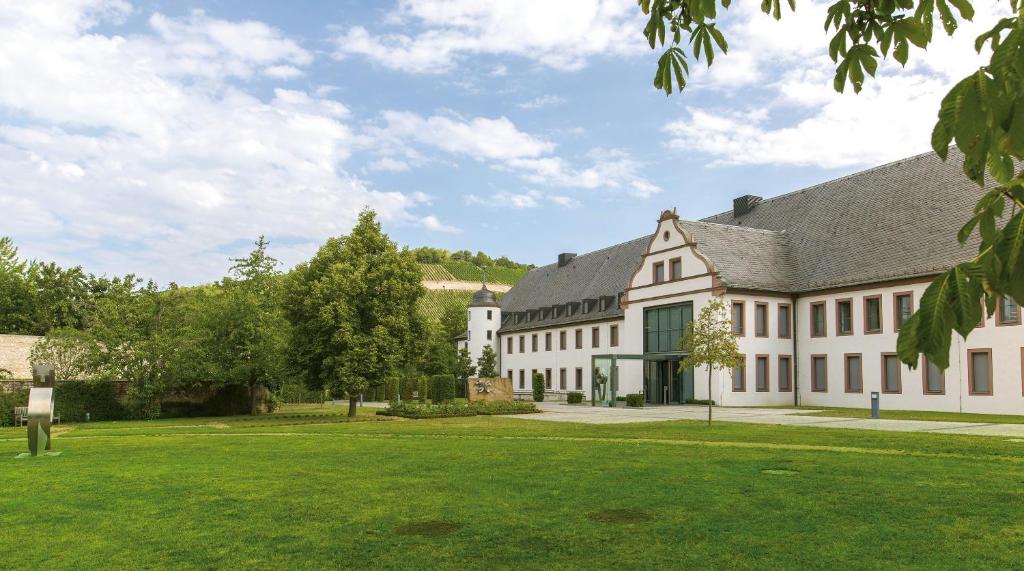 un grand bâtiment blanc avec une pelouse verte dans l'établissement Tagungshaus Himmelspforten - Self Check-In, à Wurtzbourg