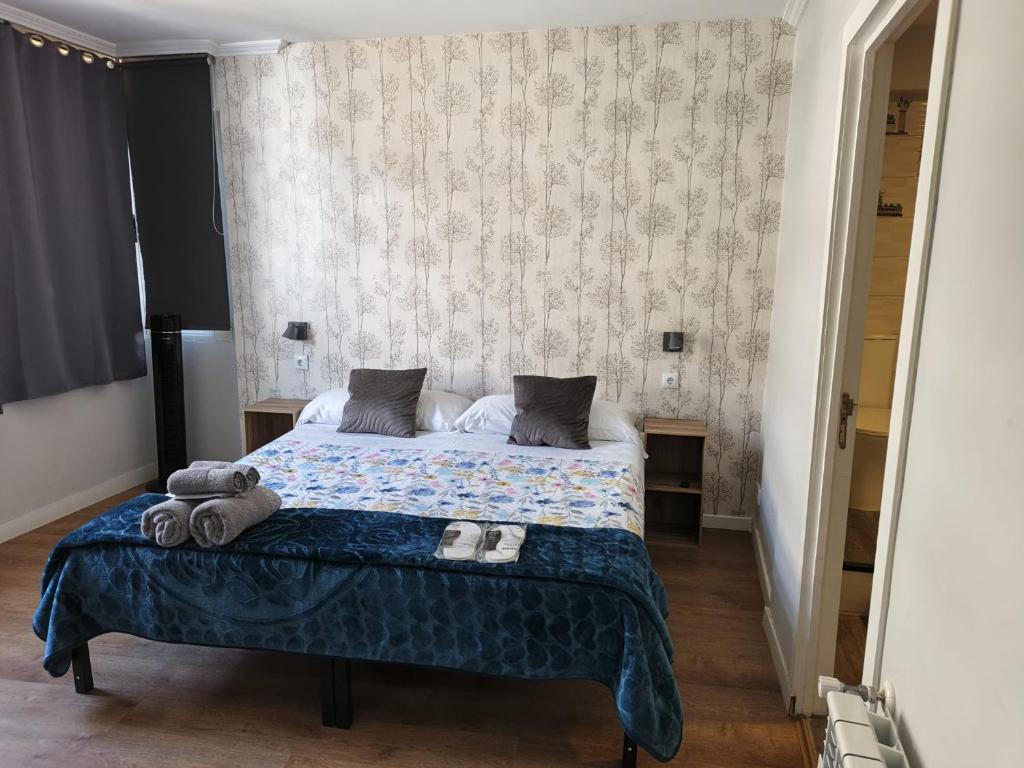 a bedroom with a large bed with a blue blanket at Pensión Casa Douro in Santiago de Compostela