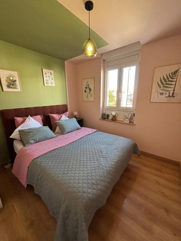 a bedroom with a large bed with pink and green walls at Résidences Les Murots 1 in Saint-André-les-Vergers