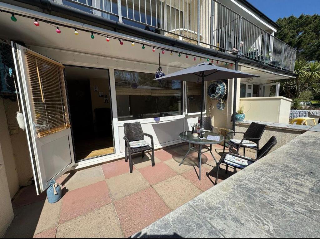 a patio with a table and chairs and an umbrella at 2 Bedroom - Seaside Apartment in Dawlish Warren