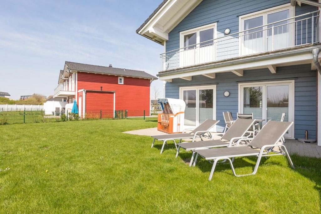 a group of lounge chairs on a lawn in front of a house at Ferienhaus Kampfläufer in Dagebüll