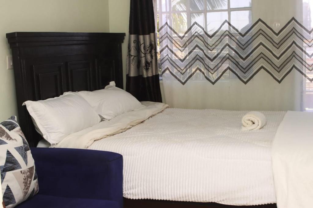 a bedroom with a white bed and a window at The Quiet Nest in Ruiru