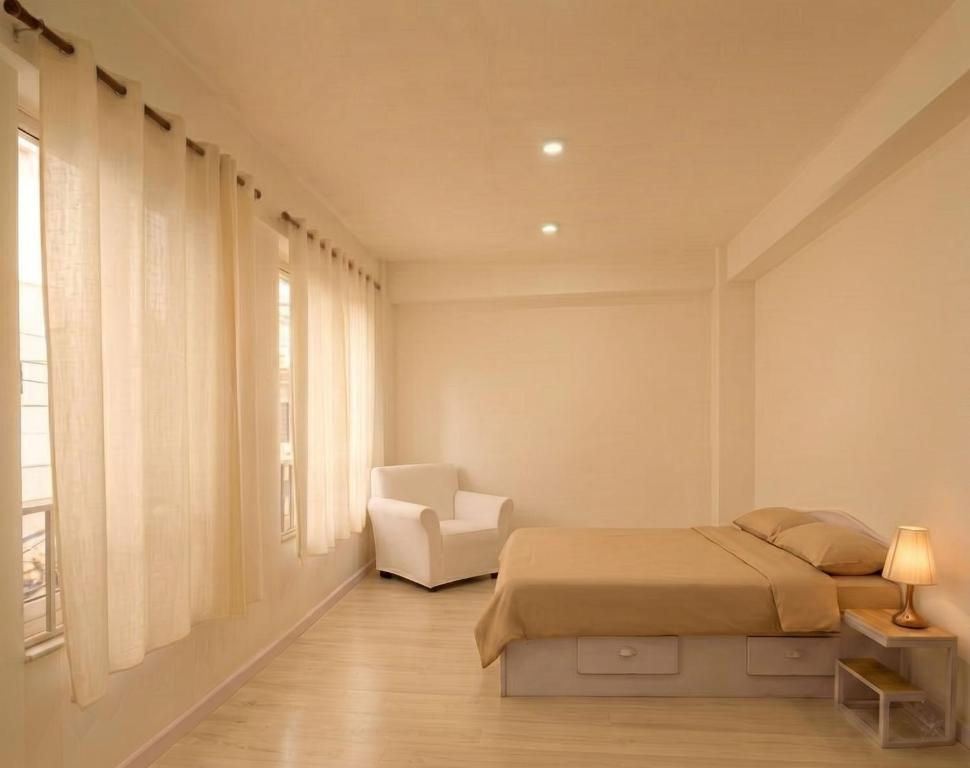 a bedroom with a bed and a chair and a window at BasantapurRooms in Kathmandu
