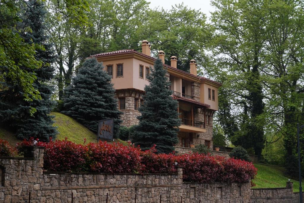 ein Haus auf einem Hügel mit einer Steinmauer in der Unterkunft Roes Suites in Kato Loutraki
