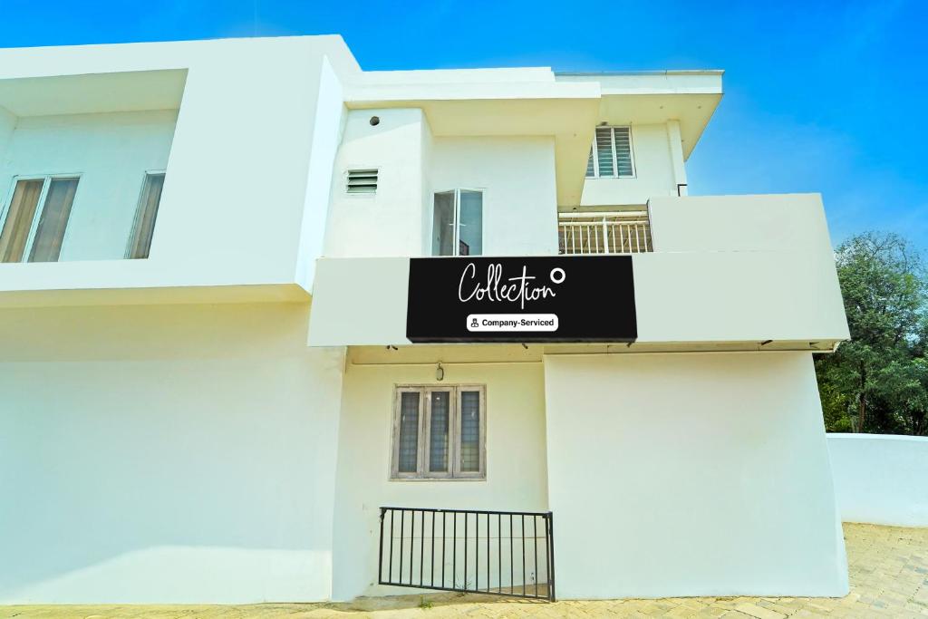 a white house with a black sign on it at Super Collection O Kureepuzha Kollam in Kollam