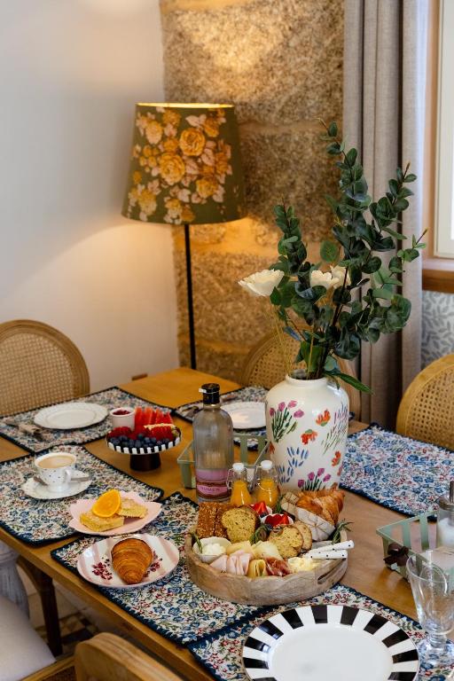 a table with a plate of food and a vase at Hotel Boutique Cata & Rose - Exclusivo y tranquilo en O Grove in O Grove