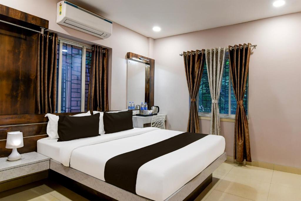 a bedroom with a white and black bed and a window at Super Collection O New Town Near OM Sweets Formerly Shiva Inn in kolkata