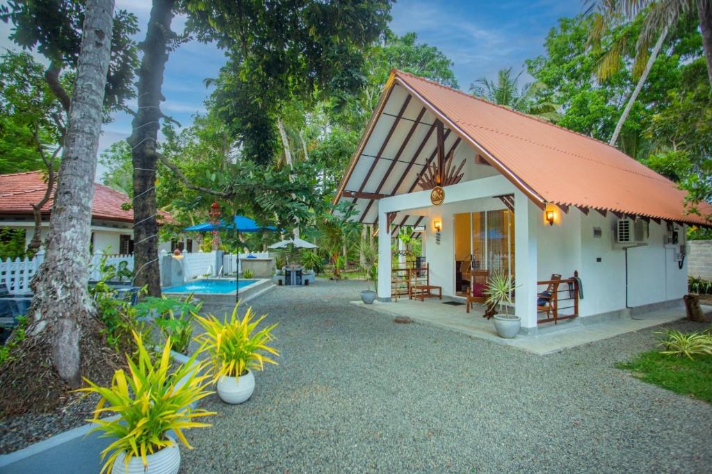 a cottage with a red roof and a patio at Ceylon Princes Villa in Ahangama