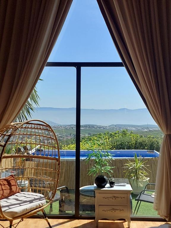 a room with a large window with a rattan chair at צימר תומר דבורה-קצה ההר in Kerem Ben Zimra