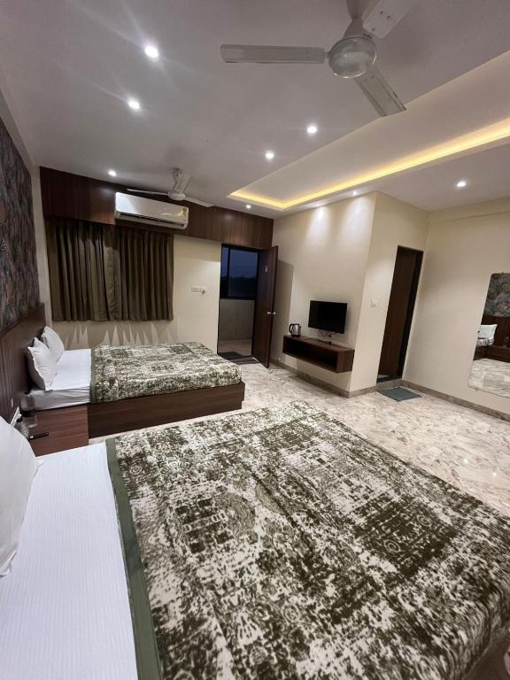 a hotel room with two beds and a television at Hotel Ashoka Resort in Ellora