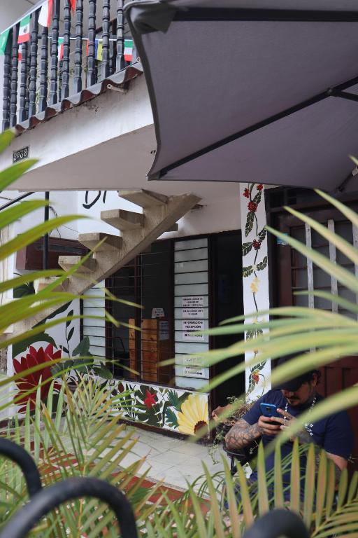 a person sitting outside of a building looking at a cell phone at Bau420! Backpackers HOSTAL in Cali