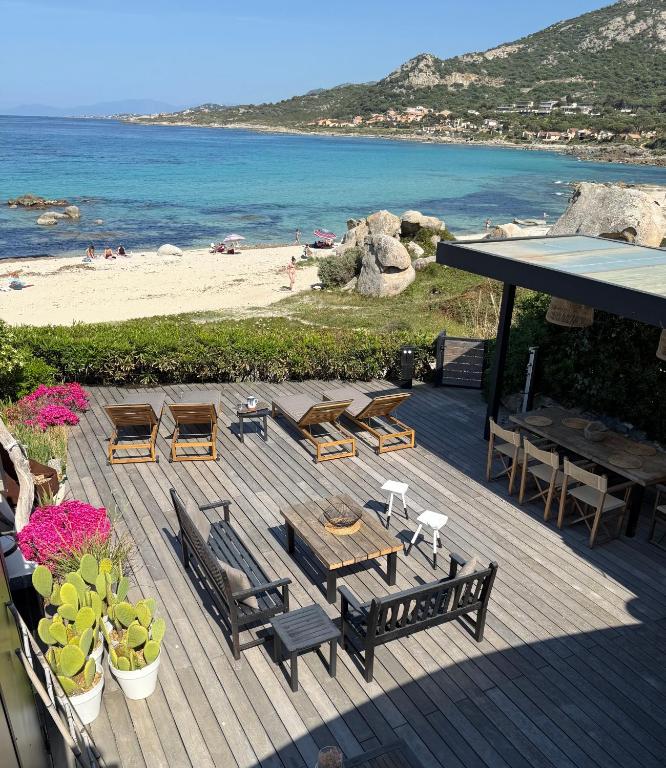 a deck with a table and chairs and a beach at Maison les pieds dans l'eau - de 2 à 6 personnes in Lumio