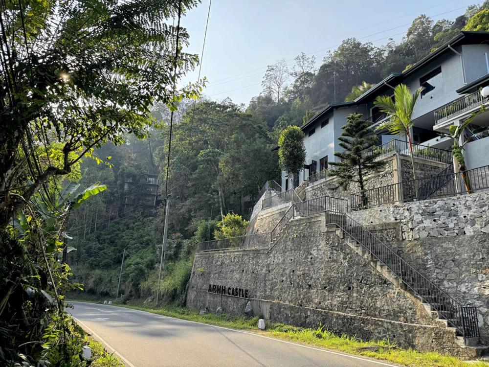 a road with a stone wall next to a house at ARHH castle in Ginigathena