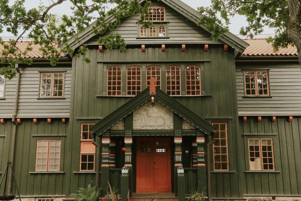 an old green house with a red door at Badhotellet Villa Berg in Norrtälje
