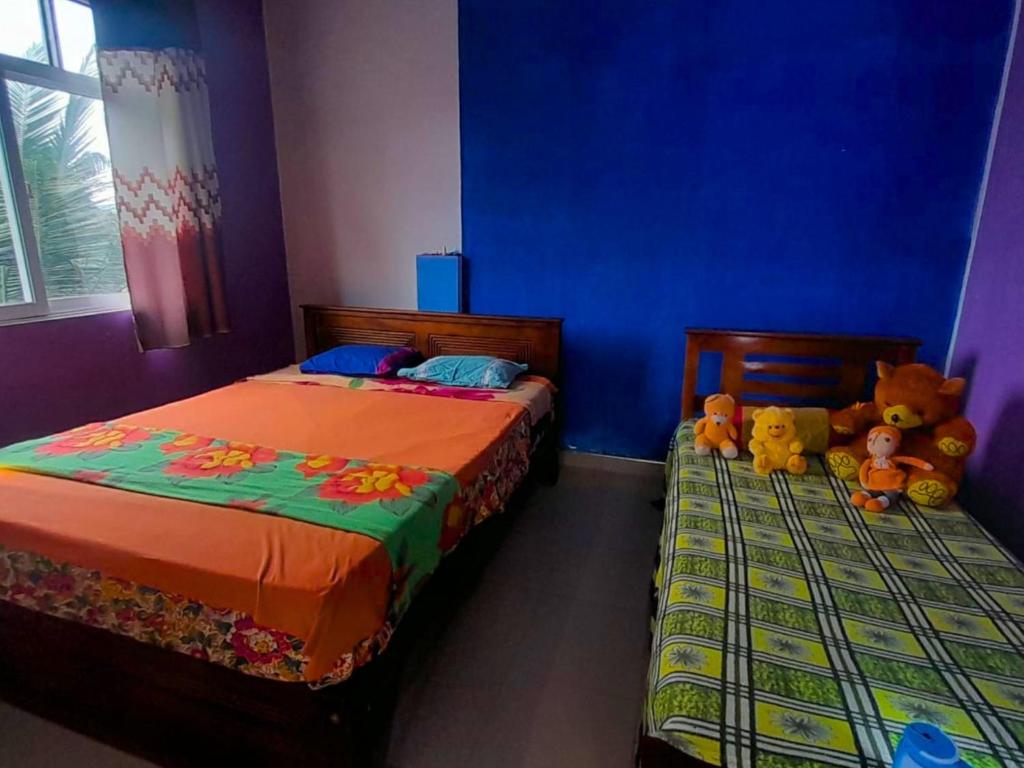 two beds in a bedroom with two stuffed animals at Ice mango homestay Badulla in Badulla
