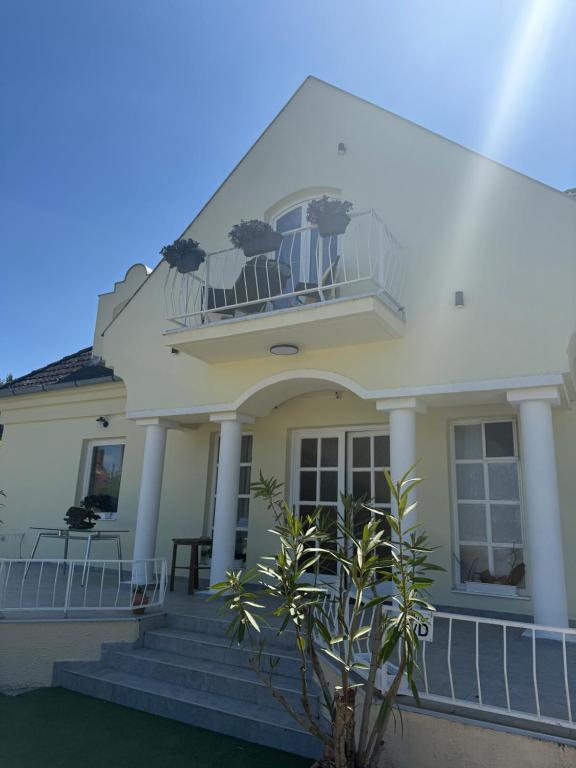 a white house with stairs and a balcony at Boróka-ház Mohács in Mohács