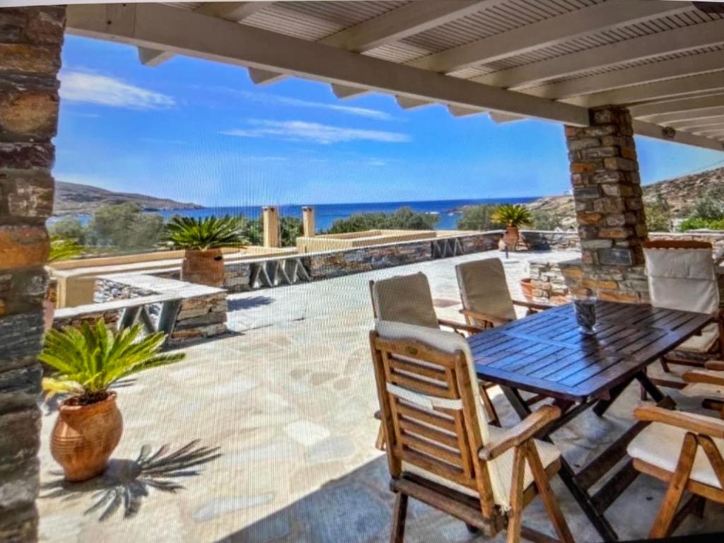 a patio with a table and chairs and a view of the ocean at Villa Vassia in Koundouros