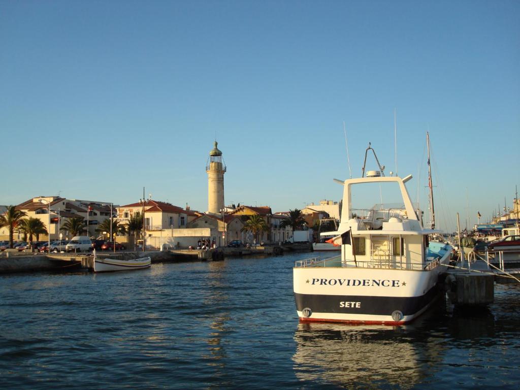 un bateau est amarré dans un port avec un phare dans l'établissement Grau du Roi Le Sémaphore, au Grau-du-Roi