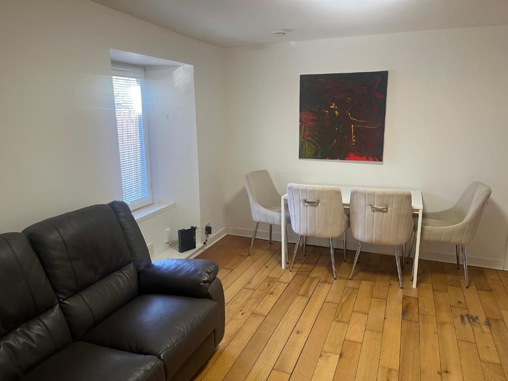 a living room with a couch and a table and chairs at Lower Mill Apartment in Newmilns