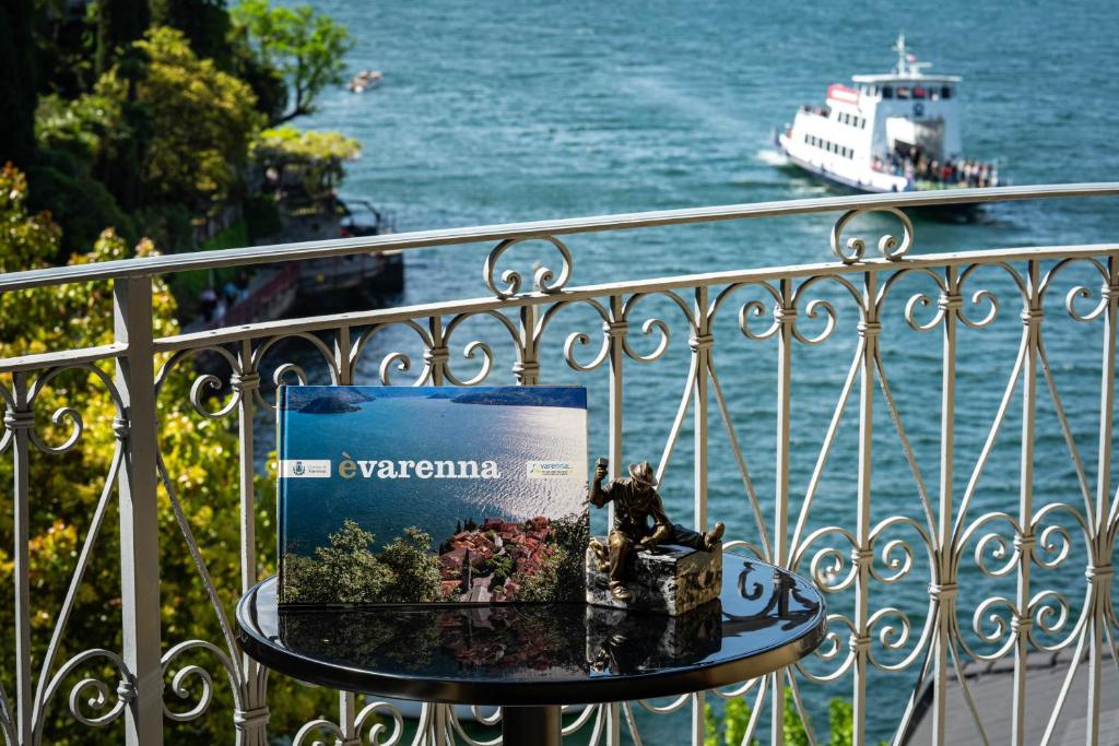a book on a table on a balcony with a boat in the water at Marble House Varenna Lake Como in Varenna