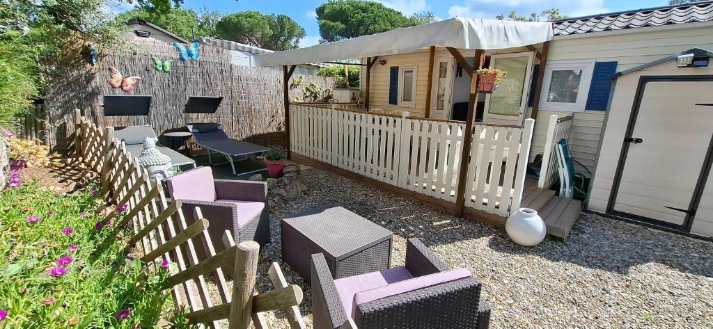 a patio with chairs and a house with a fence at Mobil home proche Fréjus - Camping 4 étoiles in Puget-sur-Argens