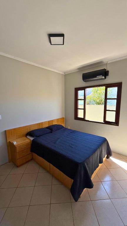 a bedroom with a bed with a blue comforter and a window at Pousada Barcelos Florianópolis in Florianópolis