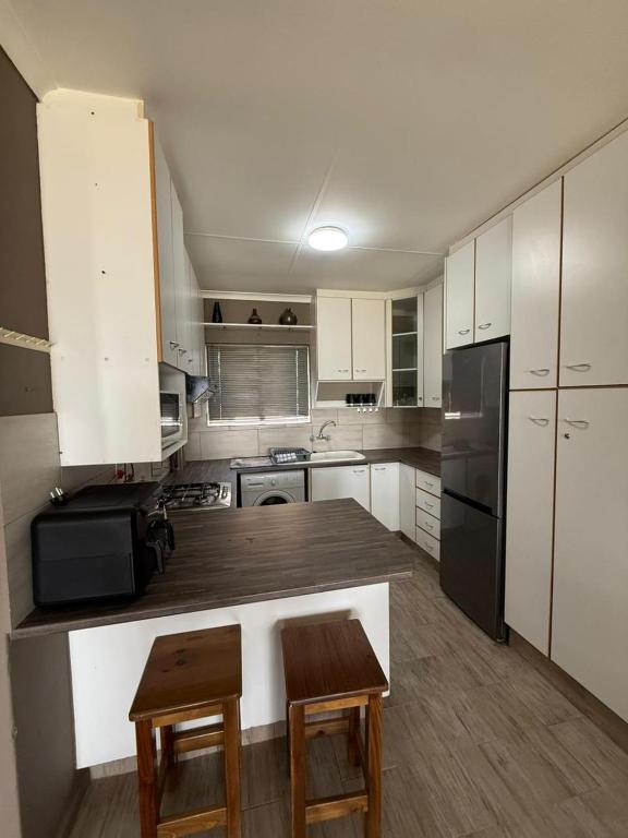a kitchen with white cabinets and a black refrigerator at Marina stunning escape in Jeffreys Bay