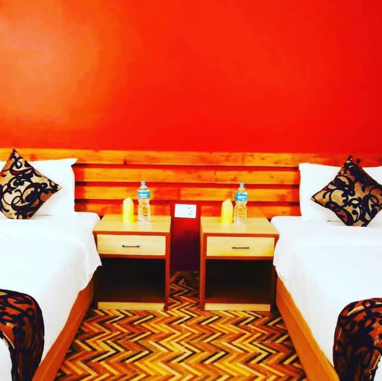 a red room with two beds and two tables at YHA Backpacker Hostel Sauraha in Sauraha