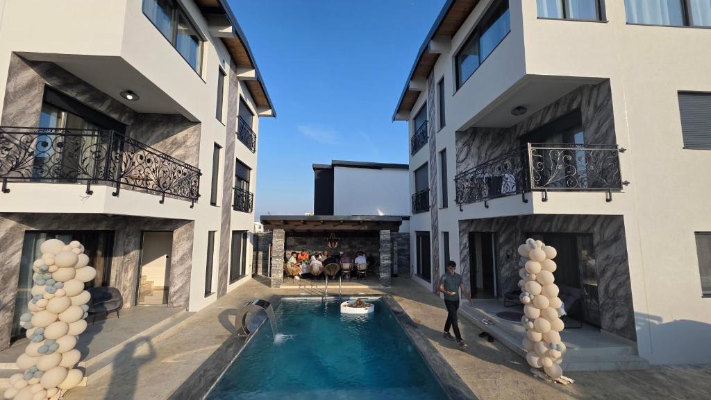 a man standing in front of a building with a swimming pool at Vile Relax in Donji Štoj