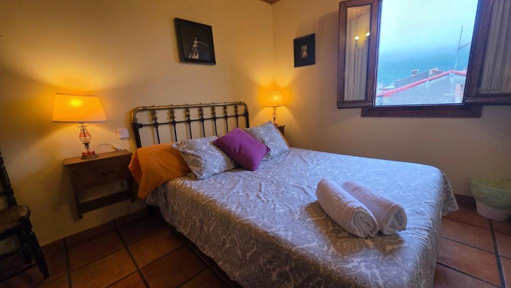 a bedroom with a bed with two pillows and a window at Casa Rural TioMoreno by Naturadrada in La Adrada