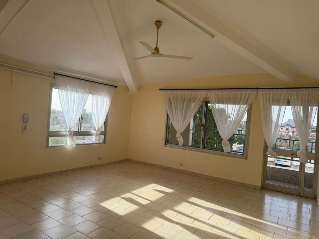 an empty room with windows and a ceiling fan at Lilia Business Hotel in Ouagadougou