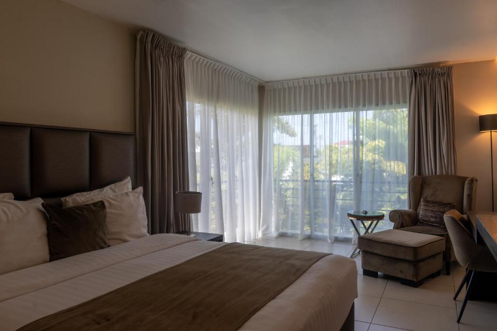 a hotel room with a bed and a chair and a window at Tucan Resort & Spa in Paramaribo