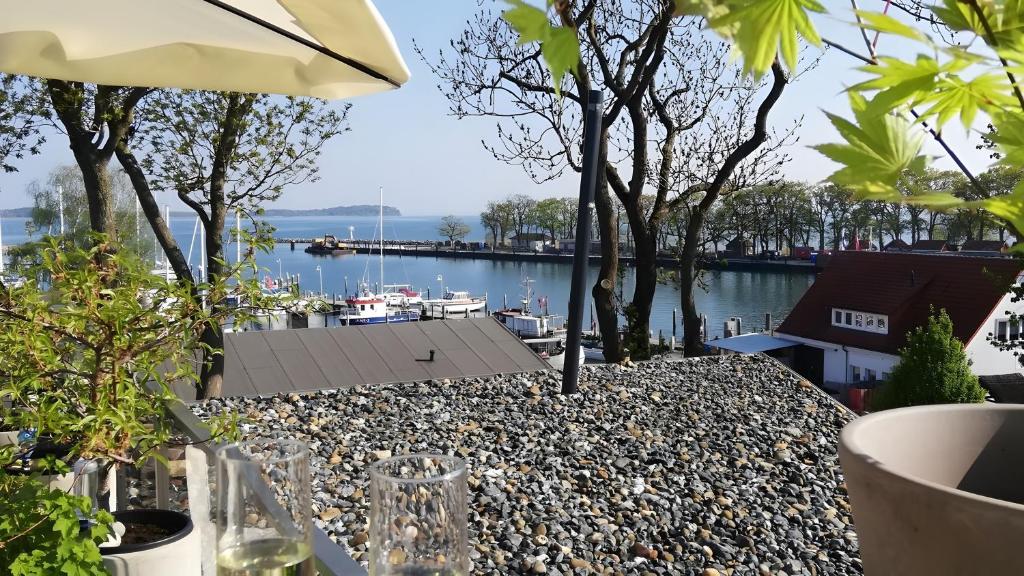 a table with glasses and an umbrella next to a body of water at Ferienwohnung Boddenblick-Vilm in Putbus