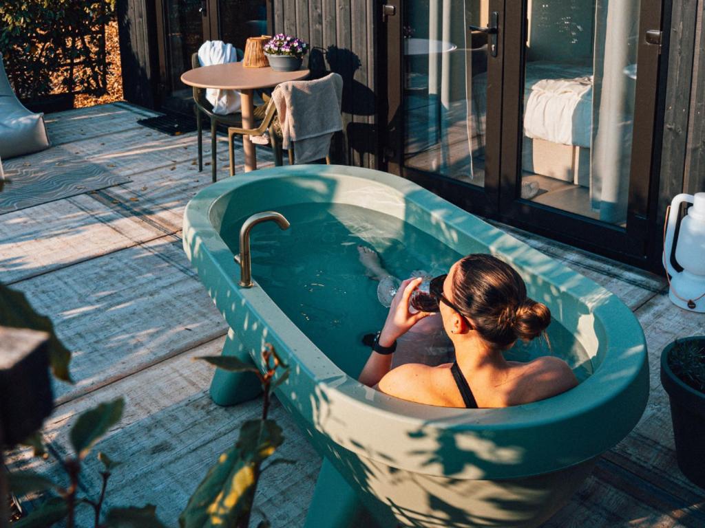 a woman sitting in a bath tub on a patio at Luxe Tiny Suite met privé tuinbad in Meerssen