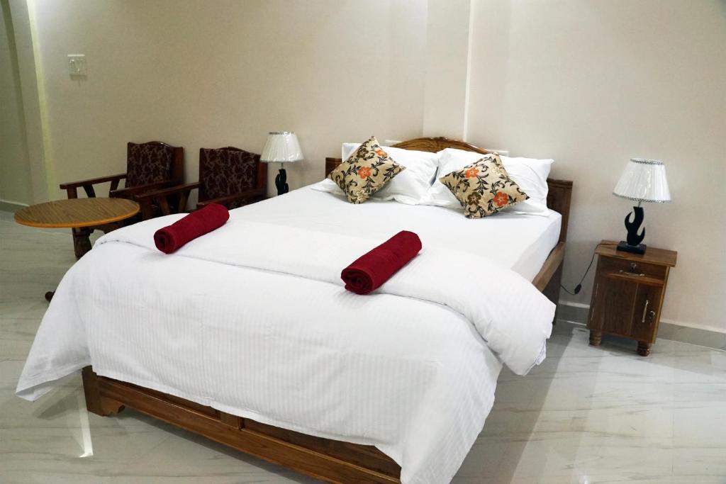 a bedroom with a large white bed with red pillows at Pritams Cottages Guest House in Palolem