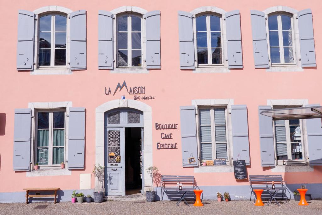 a pink building with a door and benches in front at La Maison de Laulie in Bagnères-de-Bigorre